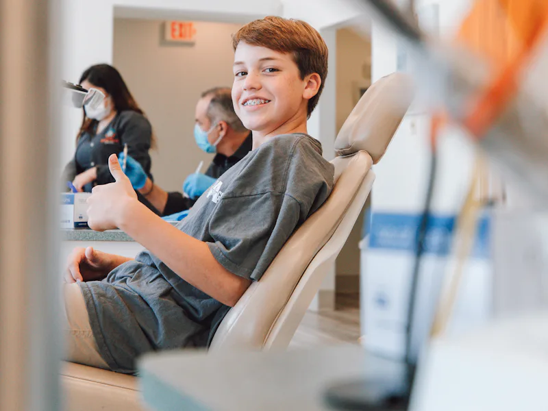 Smiling boy giving a thumbs up from a dental chair
