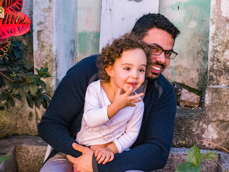 Man in glasses holding a toddler on his lap on garden steps