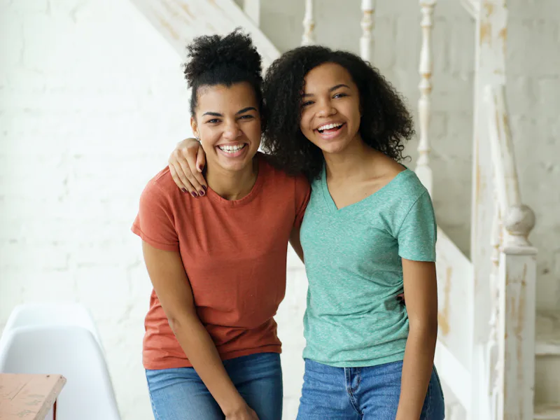 Two young women smiling with their arms around each other