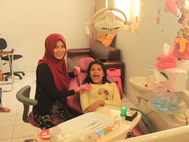 Smiling girl in a dental chair next to a dental team member