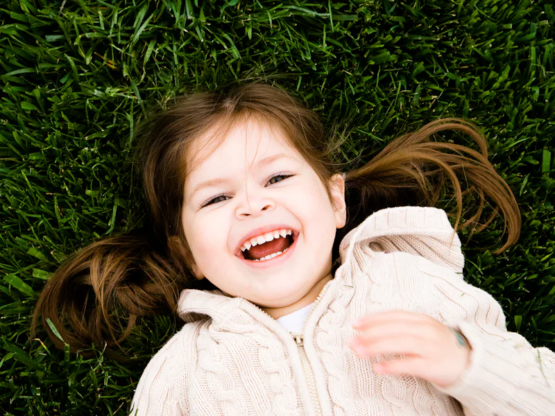 Little girl laughing while lying in the grass