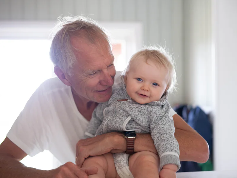 Older man holding a smiling baby