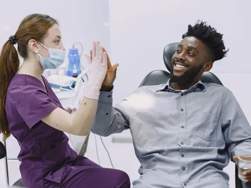 Dental hygienist and a smiling patient sharing a high five