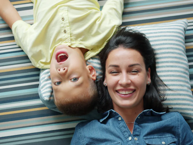 Woman and a young boy lying on a striped rug, laughing