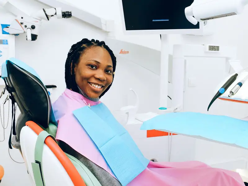 Woman smiling from a dental chair in a bright treatment room